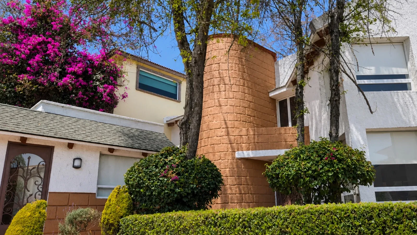 Fachada de casa con bugambilia en flor