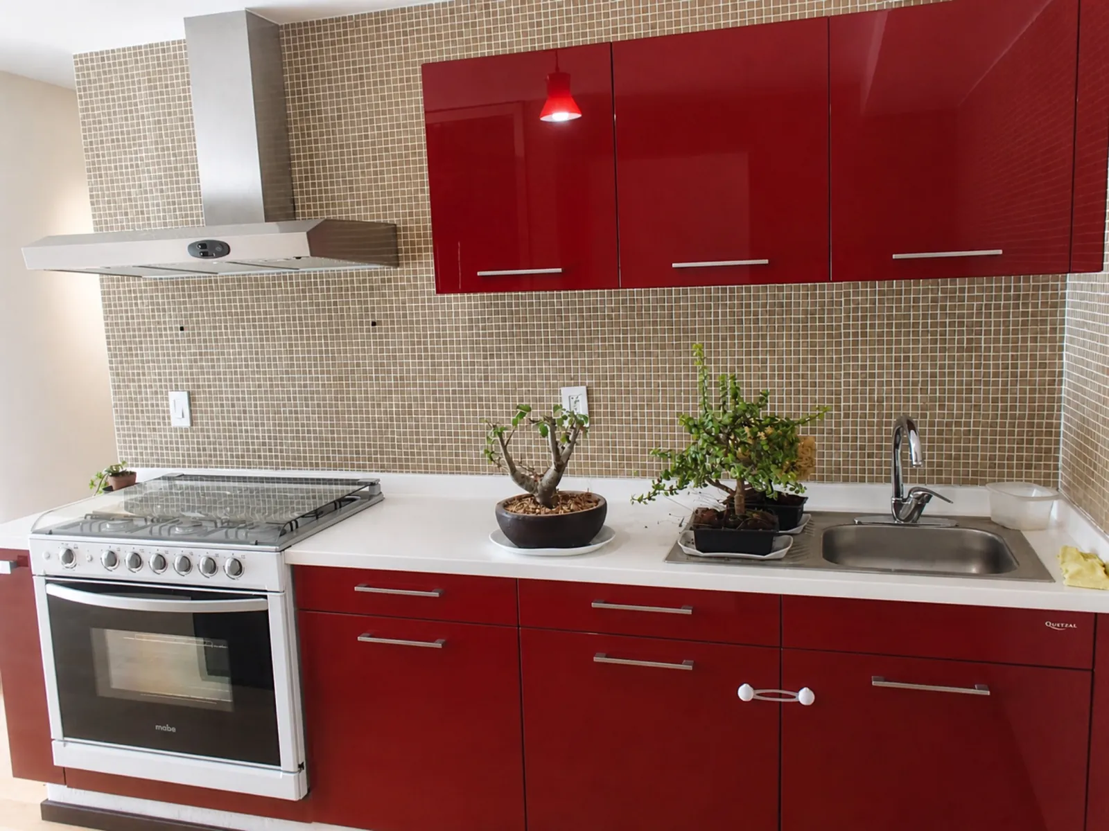 Cocina integral con alacenas rojas y cubierta blanca